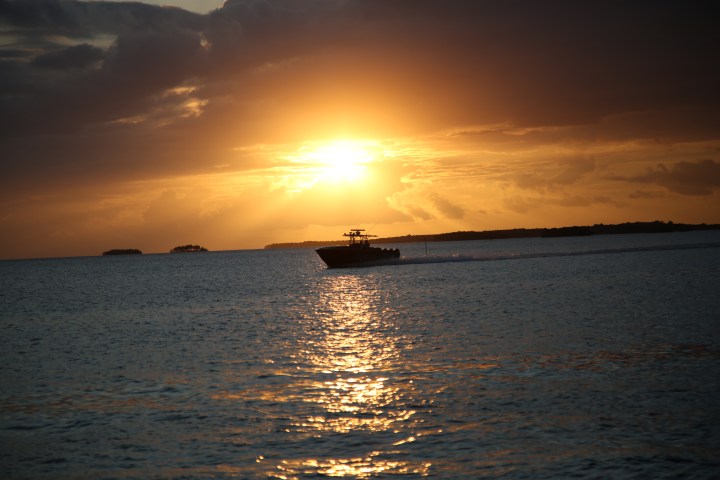 Boat on the water at sunset with an orange sky.