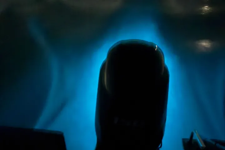 Boat motor at night creating a glowing blue wake.