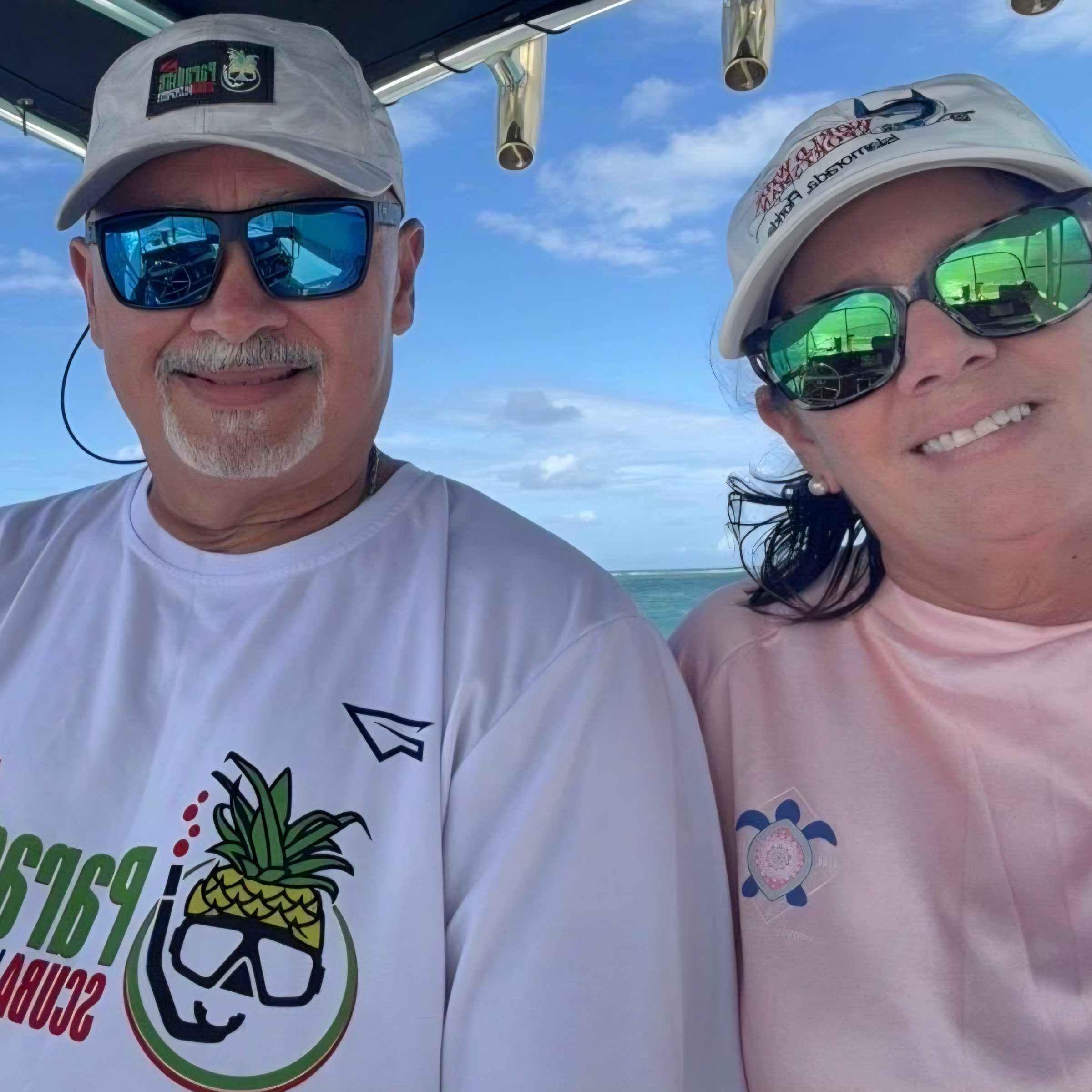 Two people smiling on a boat with sunglasses and hats.
