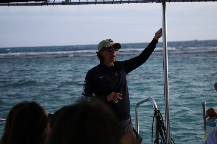 Person speaking on a boat with ocean in the background.
